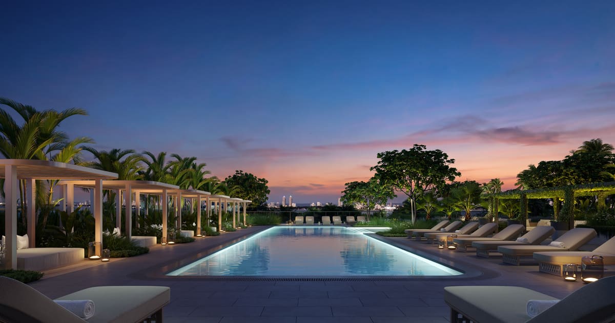 The 85-foot continuous-swim lap pool at dusk, lined with cabanas and daybeds