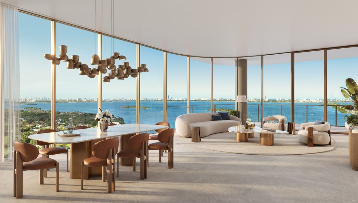 The great room of a residence with 11-foot ceilings and curved floor-to-ceiling glass framing Biscayne Bay